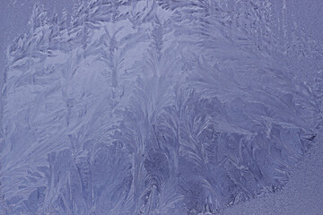 Frosty original pattern on winter glass, natural texture. Blue frosty glass ice background. Winter...
