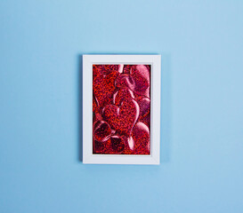 Red hearts in a white frame on a blue background, the concept of love and Valentine's day