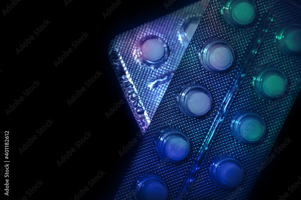 Aufkleber Pills or drugs in a package under neon light on a dark background pattern for design..