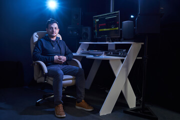 Professional male sound engineer mixing audio in recording studio. Music production technology,...