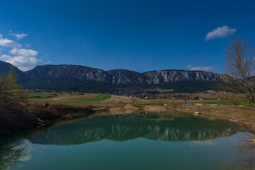 Fototapeta na wymiar reflection from long rocky mountain range in a pond with blue sky
