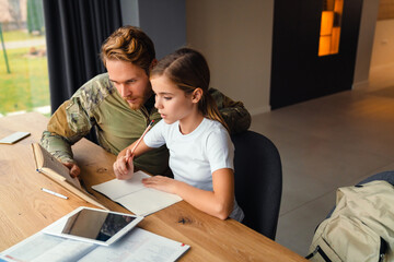 Masculine focused military man doing homework with her daughter at home