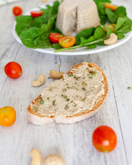 Slice of bread with vegan cashew cheese. Made with lemon juice, tahin sauce, salt and pepper