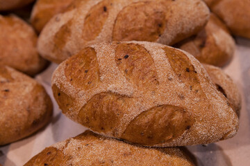 Freshly baked bread sprinkled with sesame seeds on the counter of a bakery.
