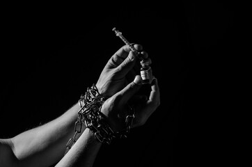 Human hands chained in chains are taking an injection into a syringe from an ampoule with a...