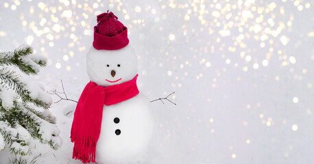 Snowman wearing a winter hat. scarf on white background with lights and standing by a tree. Christmas, New Year concept. Copy space.