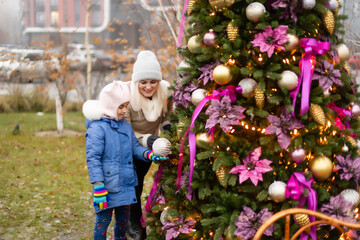 Smiling mother and daughter near Christmas tree