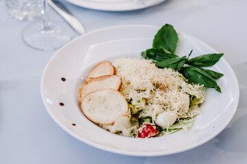 Gourmet salad in a white plate. Slices of cheese, eggs, lettuce. White plate on white table. Food. Holiday. flat lay. top view.
