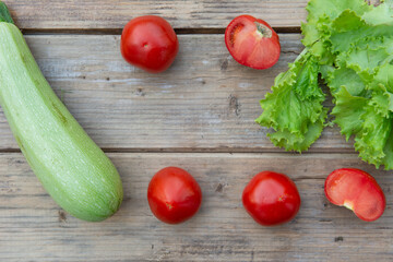 Tomatoes, zucchini and green lettuce leaves on a wooden table