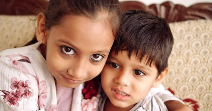 Slow-motion close of a boy and a girl playful fun enjoy naughty love care share inflating color balloons in living room on couch and fight hitting each other in between looking at camera pov