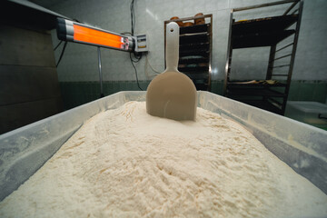 Plastic container with healthy wholegrain flour close-up. In the background is an infrared heater. Industrial bakery.