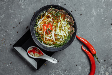 Asian cuisine, Beef soup fo in a black plate on a dark background. Soup Fo with Spicy beef broth,...