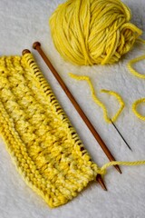 wooden knitting needles with yellow fabric and sewing needle 