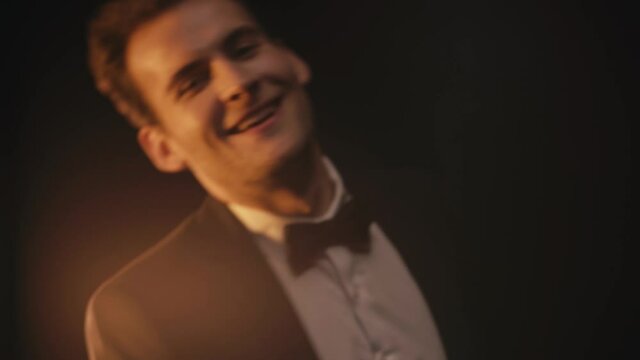 Cheerful young man in suit dancing on black background