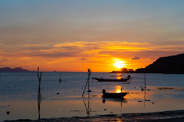 Beautiful sunset on the coast of a tropical island in Thailand, a silhouette of a boat in the ocean