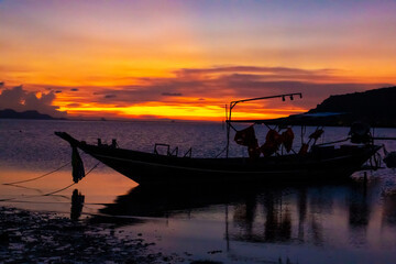 Fototapeta na wymiar Beautiful sunset on the coast of a tropical island in Thailand, a silhouette of a boat in the ocean