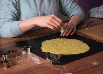 Young woman preparing christmas cookies on black baking sheet on table 