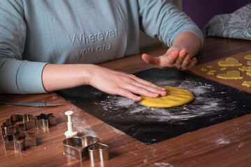 Young woman preparing christmas cookies on black baking sheet on table 