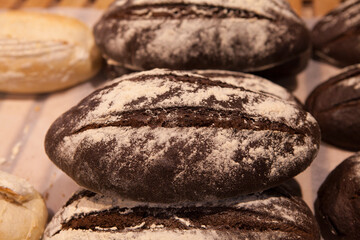 Fototapeta na wymiar Freshly baked dark bread sprinkled with sesame seeds on the counter of a bakery.