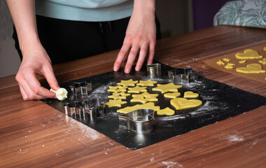 Young woman preparing christmas cookies on black baking sheet on table 