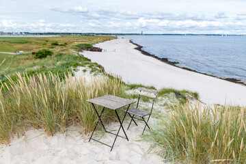 Fototapeta na wymiar Tisch und Stuhl am Strand in den Dünen 