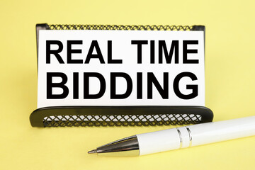 REAL TIME BIDDING, text on WHITE PAPER on a yellow background