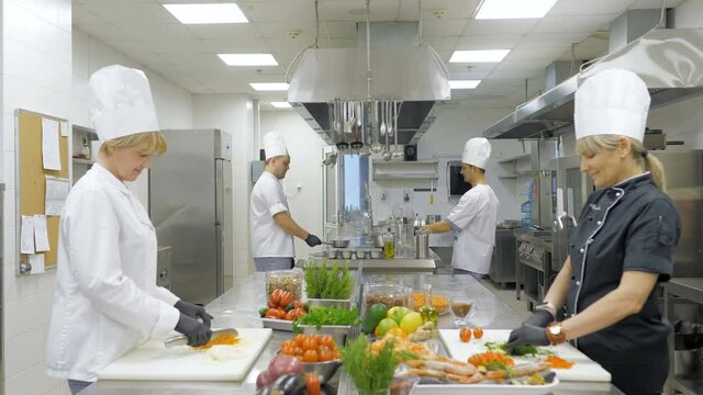 Cooks cut vegetables in the kitchen in a restaurant