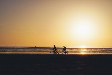 Obraz premium Surfers and people enjoying beach during sunset in Taghazout, Morocco