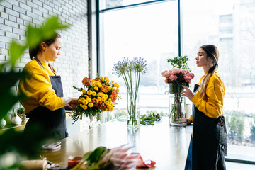 Two professional women floral artists, florists making floral bouquets with flowers at workshop, flower shop. Floristry, handmade, wedding, birthday, holiday and small business concept.