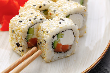 Sushi roll with salmon, philadelphia cheese and sesame on plate close up