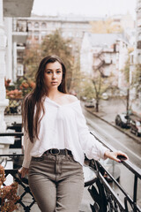 Photoshoot of a beautiful girl in a white shirt on the balcony