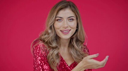 Smiling woman blowing air kiss at camera isolated on red