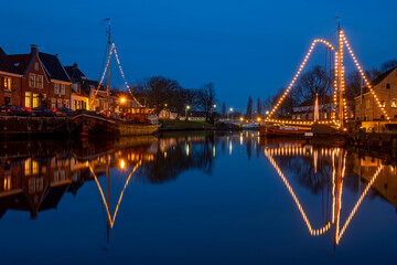 Fototapeta na wymiar Decorated traditional boats in the harbor from Dokkum in the Netherlands at christmas at sunset