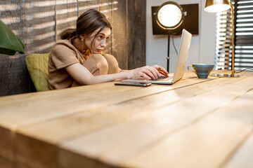 Tired woman wears domestic suit working on laptop at the cozy home office