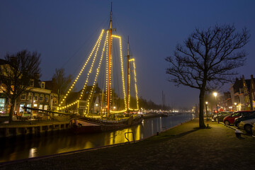Decorated traditional sailing ship in the harbor from Harlingen in the Netherlands in christmastime at night