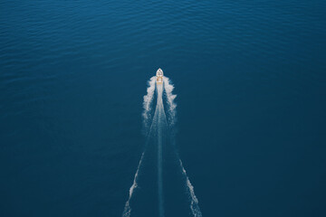 Top view of a white boat sailing to the blue sea. Drone view of a boat. Aerial view luxury motor boat. Drone view of a boat the turquoise clear waters.