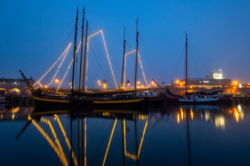 Fototapeta na wymiar Decorated traditional sailing ship in the harbor from Harlingen in the Netherlands in christmastime at night