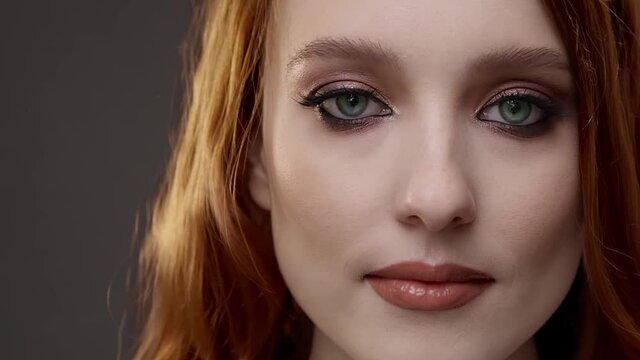 Redhead girl in model studio, with changing eyes from green to blue. Concept - contact lenses, eyes, glasses, hair dye.