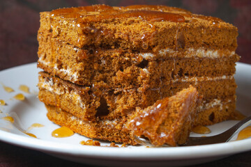 honey cake with honey drips lies on a white plate