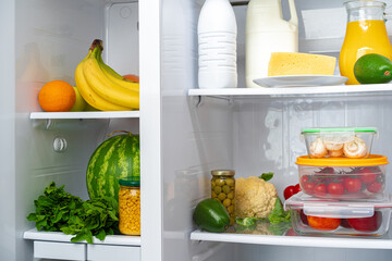 Open fridge full of fruits, vegetables and drinks