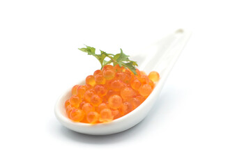 Closeup of trout eggs in a white ceramic spoon on white background