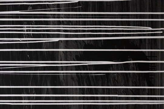 black concrete wall with white streaks of white paint. rough surface texture
