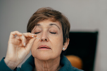 Portrait Senior woman taking a auto test for COVID-19 at home with Antigen kit. Introducing nasal swab test for possible infection of Coronavirus. Medicine and health-related services online. - obrazy, fototapety, plakaty