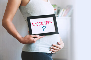 Pregnant woman holds whiteboard with text message - VACCINATION.