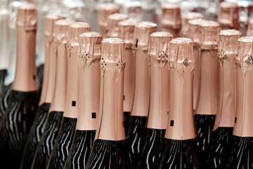 Sparkling wine bottles in golden foil for celebration. Champagne in wine store, alcohol industry