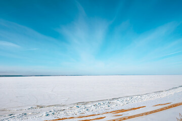 Top view of a frozen river with visible paths on a cold winter day with blue sky