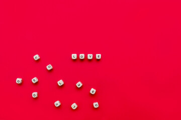 Wooden cubes with the word love on a red background next to other wooden cubes with letters. Valentine's day or wedding concept. Flat lay, top view. Love concept.