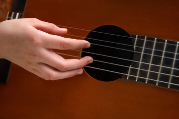 Close up of hand playing acoustic guitar. Practicing classic musical instrument. Home school...