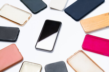 Pile of multicolored plastic back covers for mobile phone on white background. Choice of smart phone protector accessories. A lot of silicone phone backs or skins next to smart phone