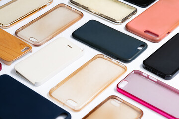 Pile of multicolored plastic back covers for mobile phone. Choice of smart phone protector accessories on white background. A lot of silicone phone backs or skins next to each other